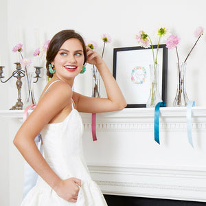 bride wearing short white bridal shower dress with ribbon tie flowers on mantle and colorful ribbons