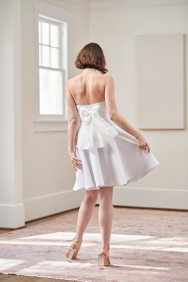 Bride wearing strapless short white cocktail dress and flattering elegant after party dress with large bow