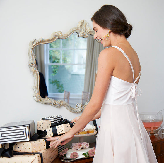 Beautiful happy bride wearing stylish designer short bridal shower dress opening presents at bridal shower party