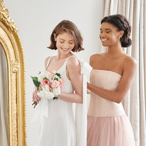 Beautiful happy bride wearing elegant white wedding gown with maid of honor in blush pink tulle bridesmaid wedding dress