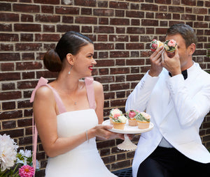 Bride wearing designer short white wedding dress and chic bridal shower dress with pink straps with cupcakes and groom