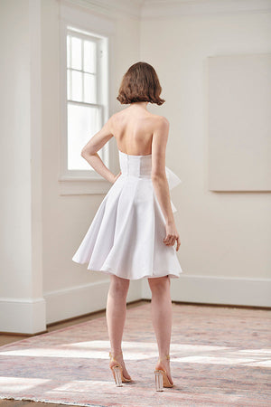 back view of bride twirling in strapless white cocktail dress with large front bow for the first dance