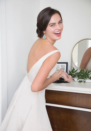 Happy bride getting ready for rehearsal dinner in backless off white dress and bridal party dress