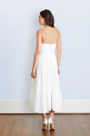 Bride wearing a feminine boho strapless tea length white flowy wedding gown to garden party bridal shower