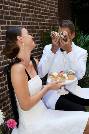 Bride holding cupcakes in short white cocktail dress chic bridal party dress with groom at rehearsal dinner