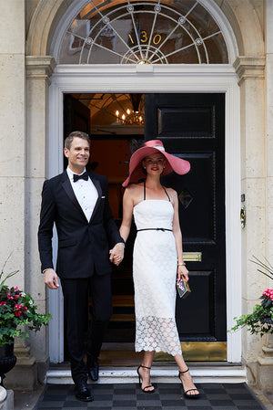 Bride and Groom leaving wedding in going away outfit. Bride wears Jane Summers Lace wedding dress and pink hat