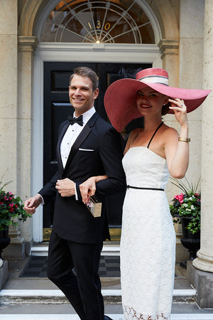 Jane Summers Bride wears white lace tea length wedding dress with a derby hat for going away dress after wedding reception with groom in tux