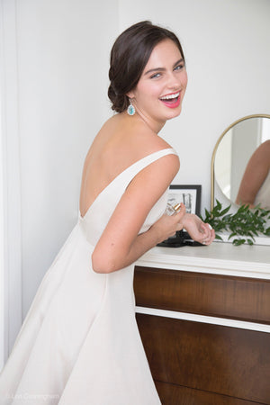Happy bride getting ready for rehearsal dinner in backless off white dress and bridal party dress
