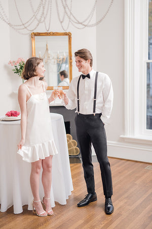 bride in short white Gatsby cocktail wedding reception and rehearsal dinner dress with groom toasting cutting cake