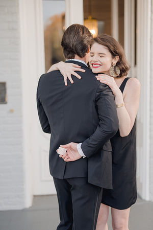 groom with engagement ring proposing to happy bride wearing little black dress